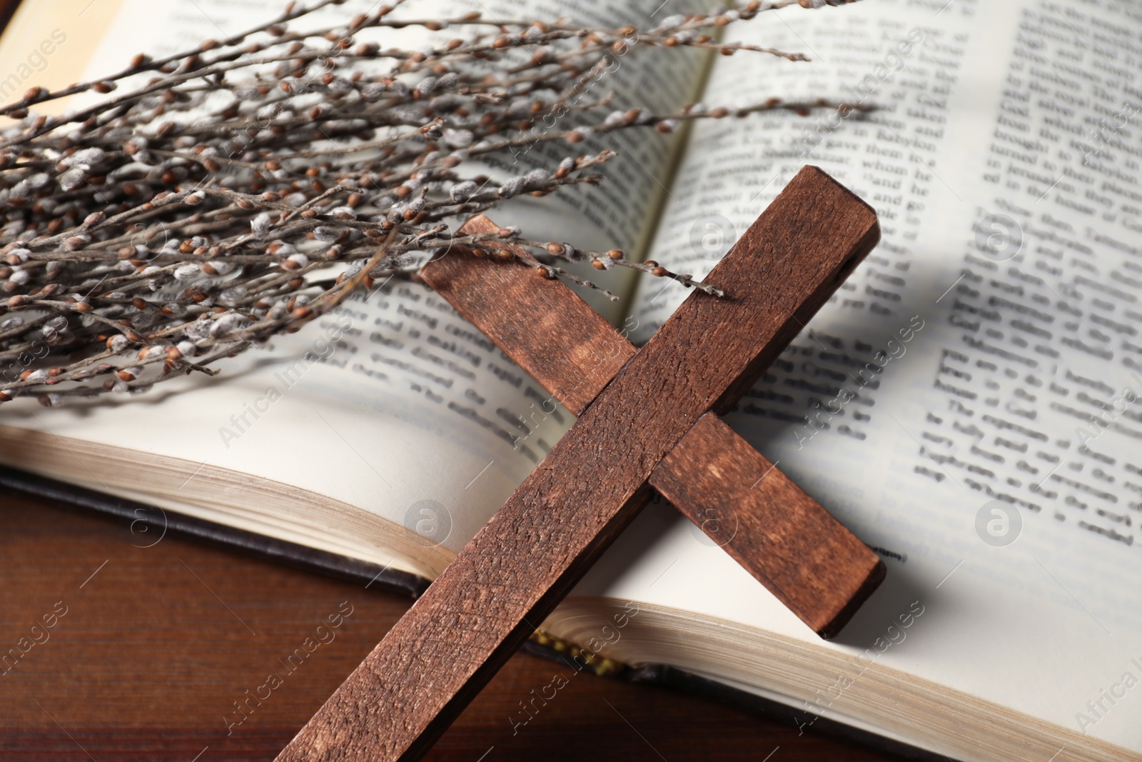 Photo of Bible, willow branches and wooden cross on table, closeup