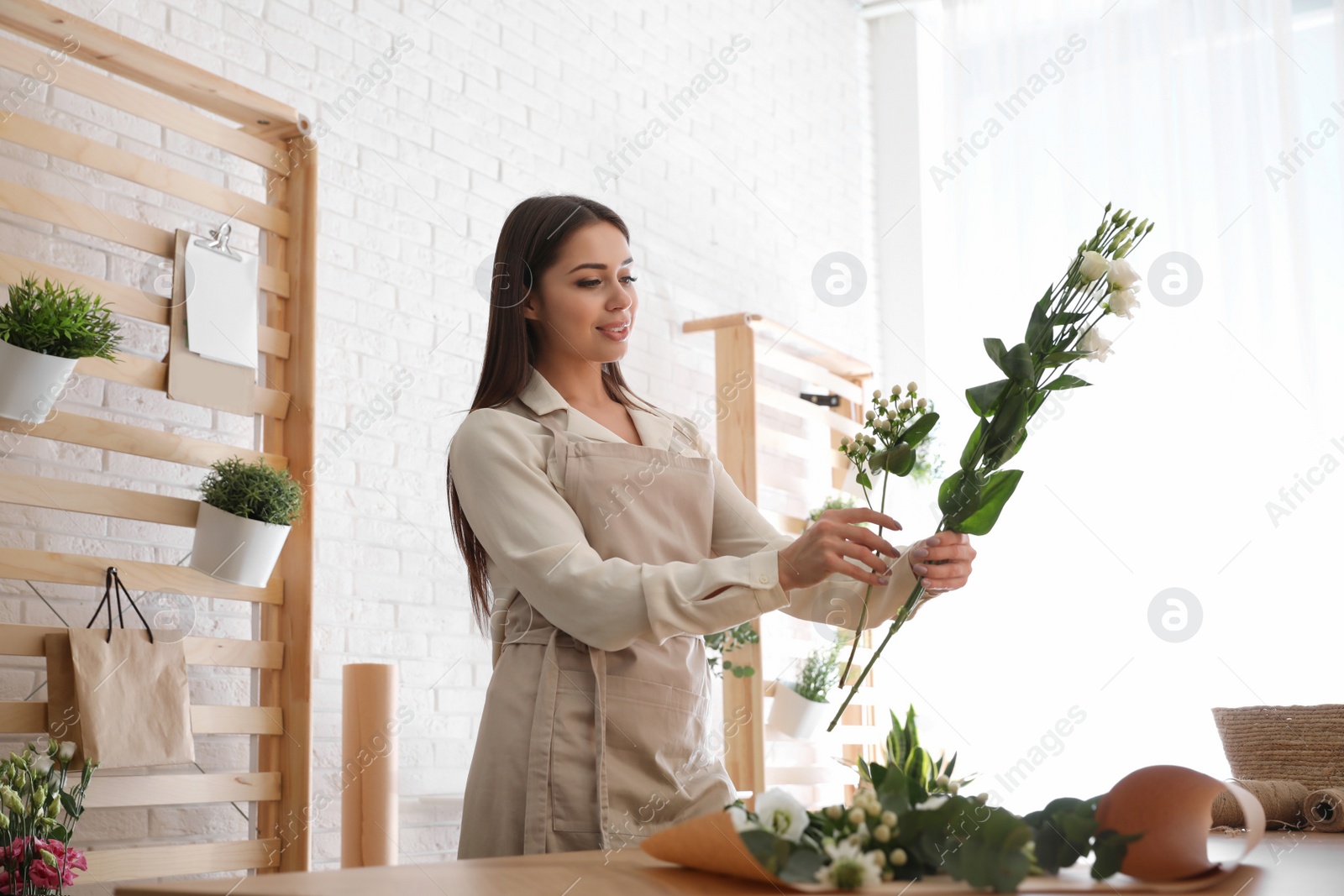 Photo of Florist making beautiful bouquet at table in workshop