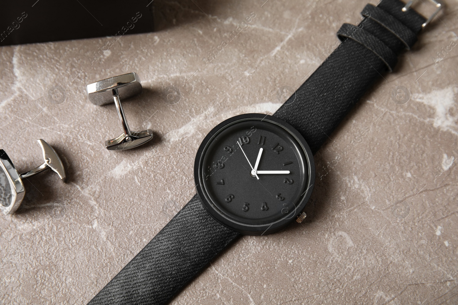 Photo of Stylish wrist watch and cuff links on table. Fashion accessory