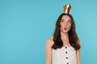 Photo of Beautiful young woman with princess crown sending air kiss on light blue background, space for text