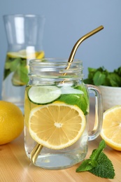 Photo of Refreshing water with cucumber, lemon and mint on wooden table