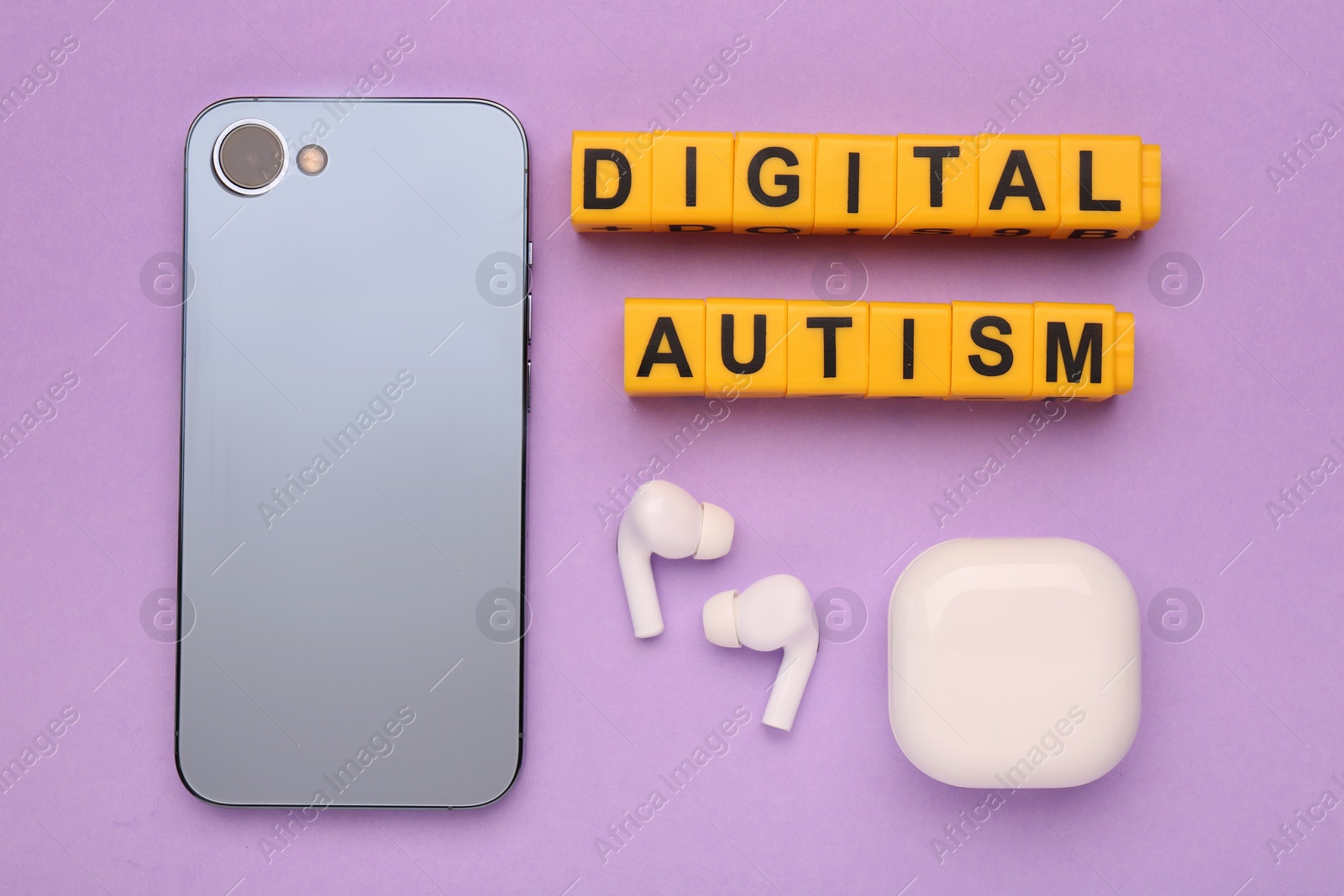 Photo of Phrase Digital Autism made of yellow cubes, smartphone and earphones on violet background, flat lay. Addictive behavior