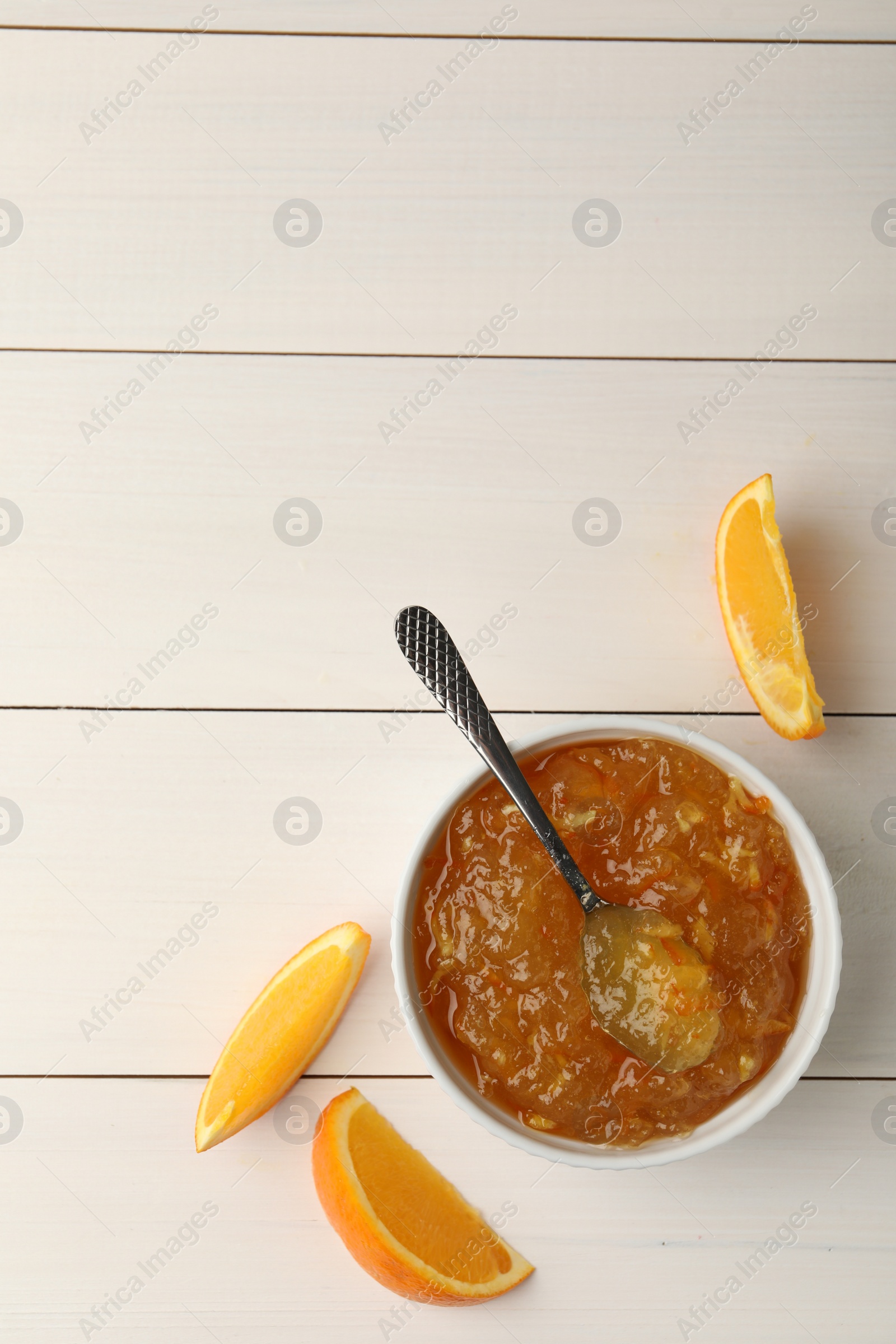 Photo of Delicious orange marmalade and fruit slices on white wooden table, flat lay. Space for text
