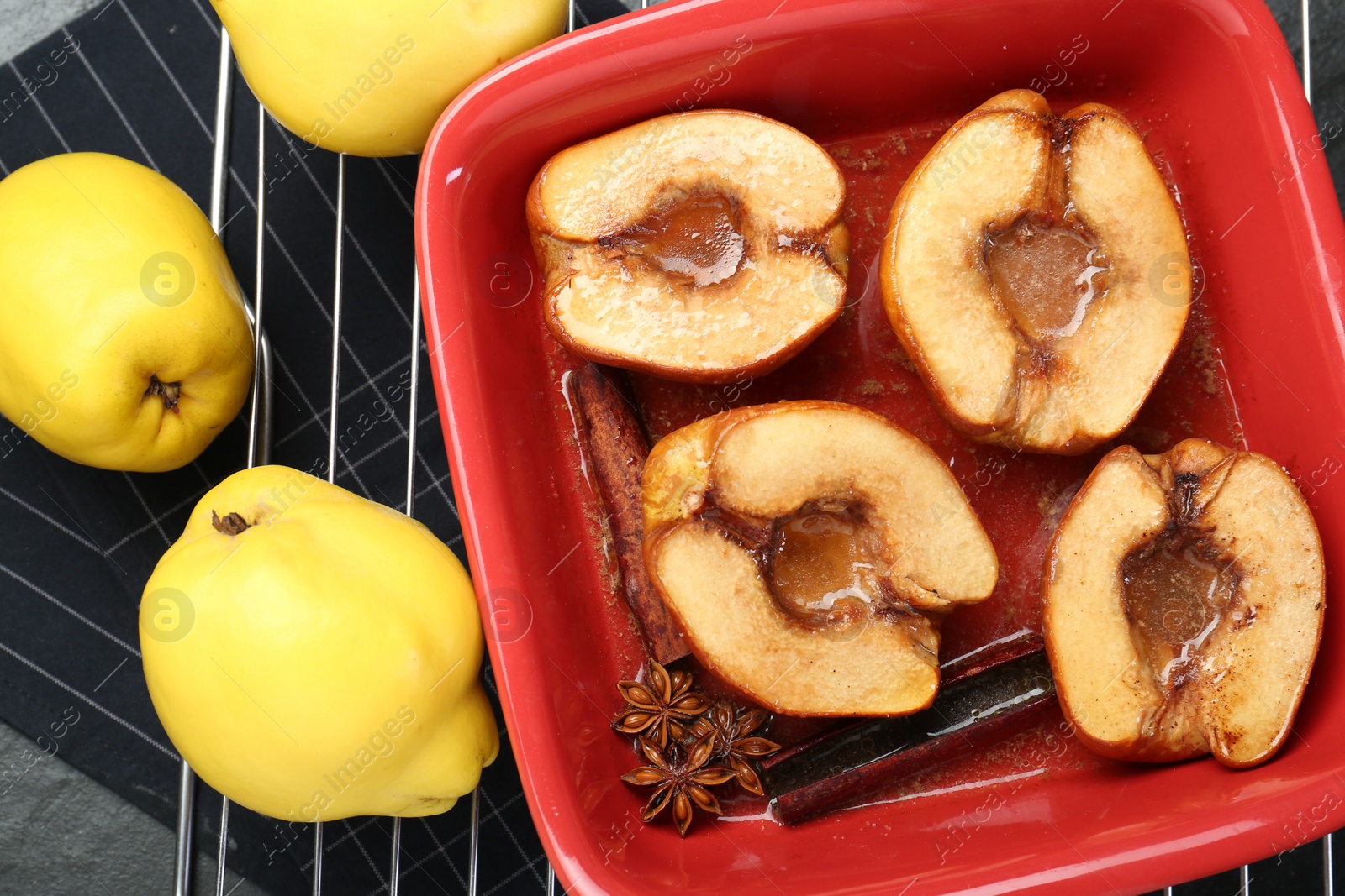 Photo of Tasty baked quinces with anise and honey in dish on black table, flat lay