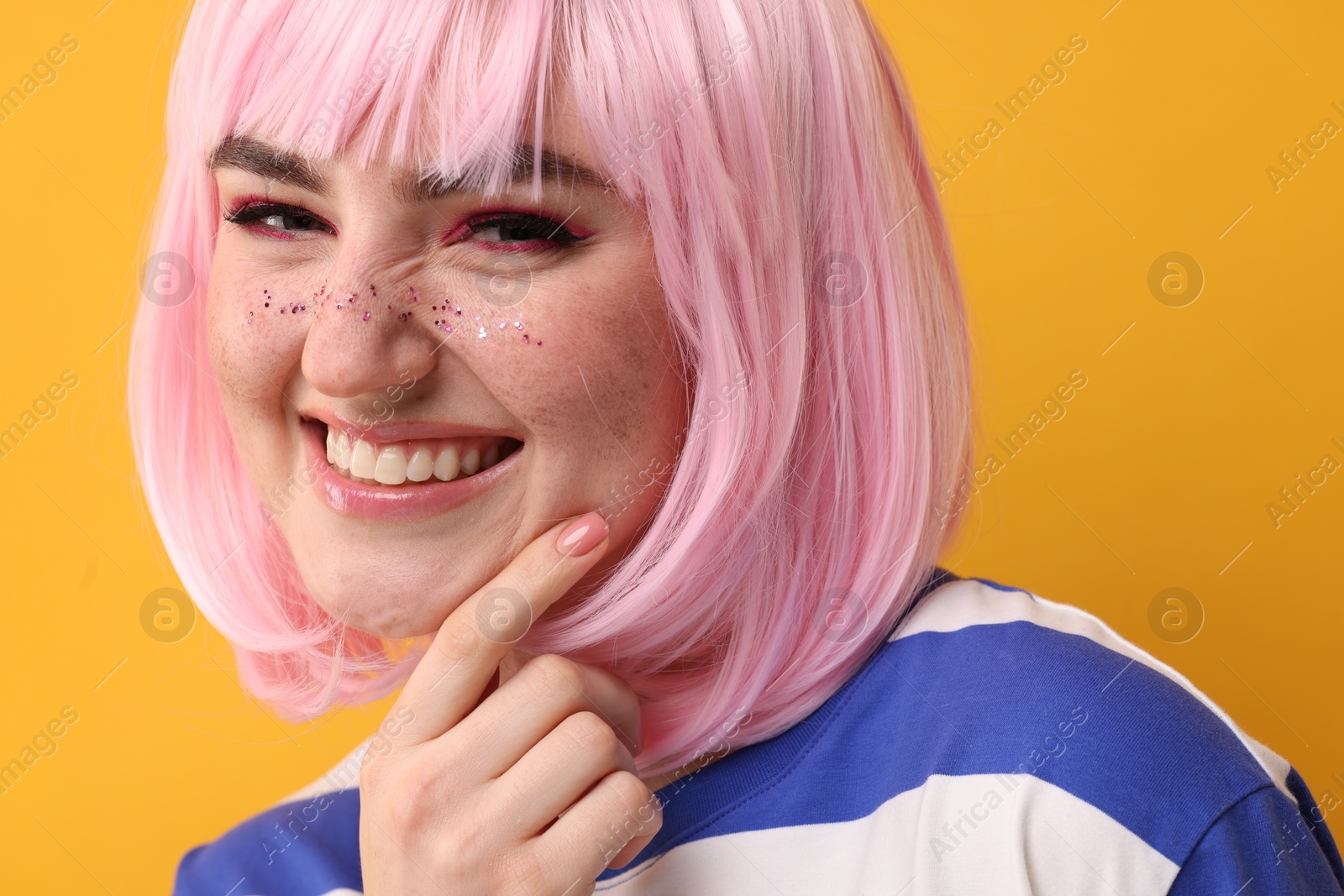 Photo of Beautiful woman with bright makeup and glitter freckles on yellow background, closeup