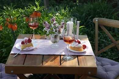 Photo of Vase with spring flowers, wine and cake on table served for romantic date in garden