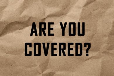 Image of Text ARE YOU COVERED? on brown crumpled paper background. Insurance concept