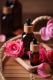 Photo of Bottles of essential rose oil and flowers on tray
