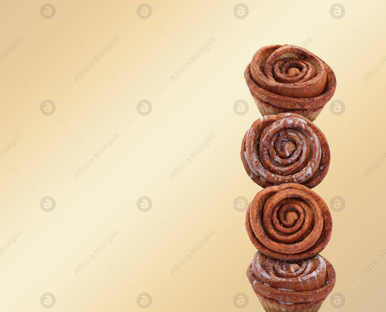 Image of Cinnamon rolls balancing on golden background, space for text