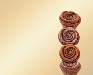 Image of Cinnamon rolls balancing on golden background, space for text