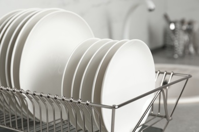 Photo of Drying rack with clean dishes on kitchen counter