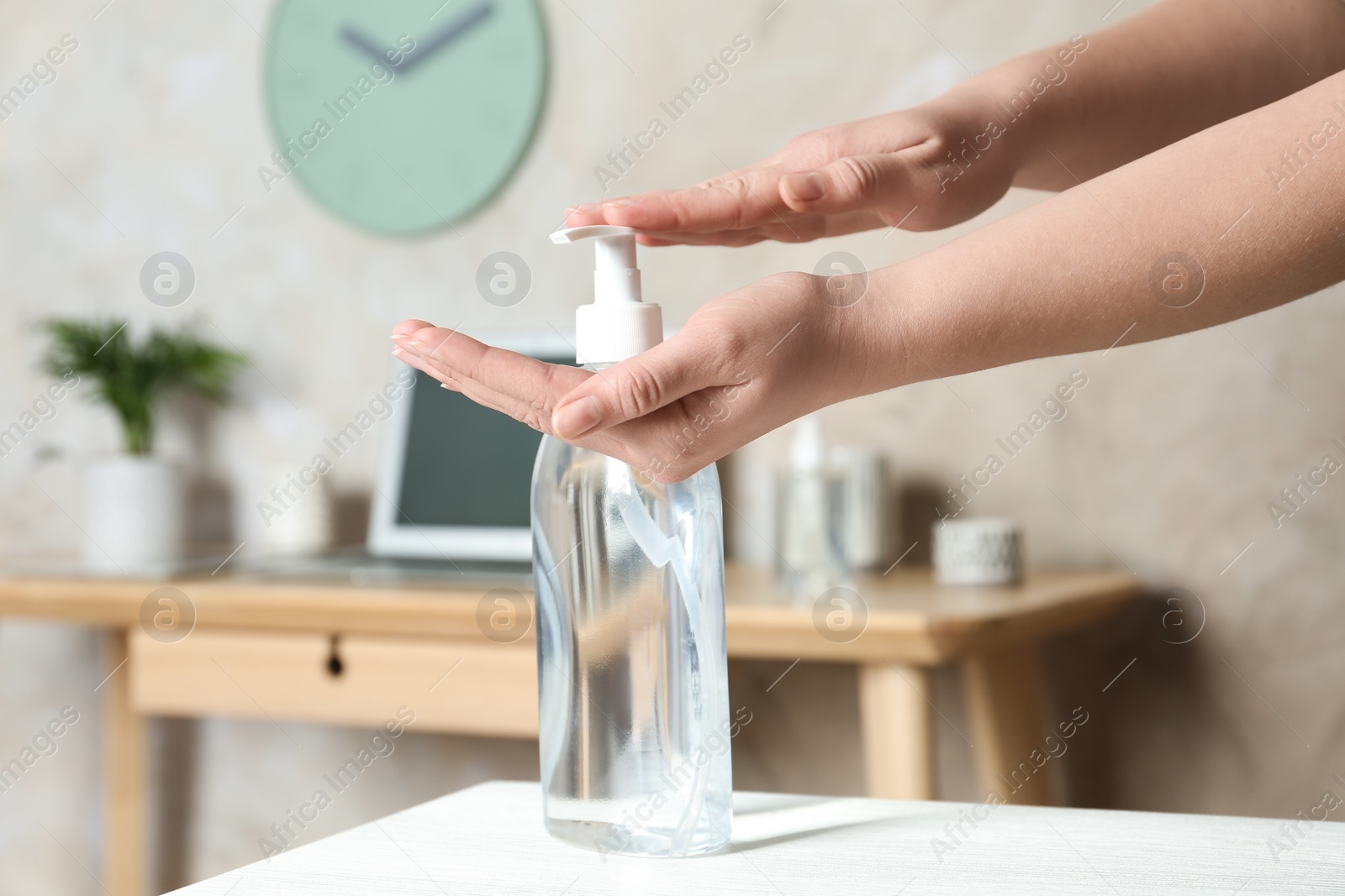 Photo of Woman applying antiseptic gel on hand indoors, closeup