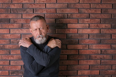 Senior man in state of depression near brick wall