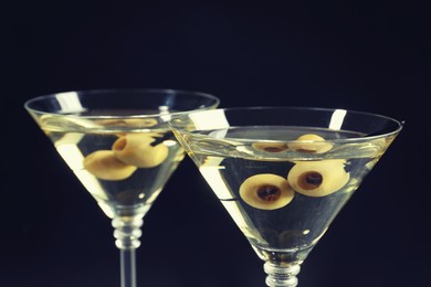Photo of Martini cocktails with olives on dark background, closeup