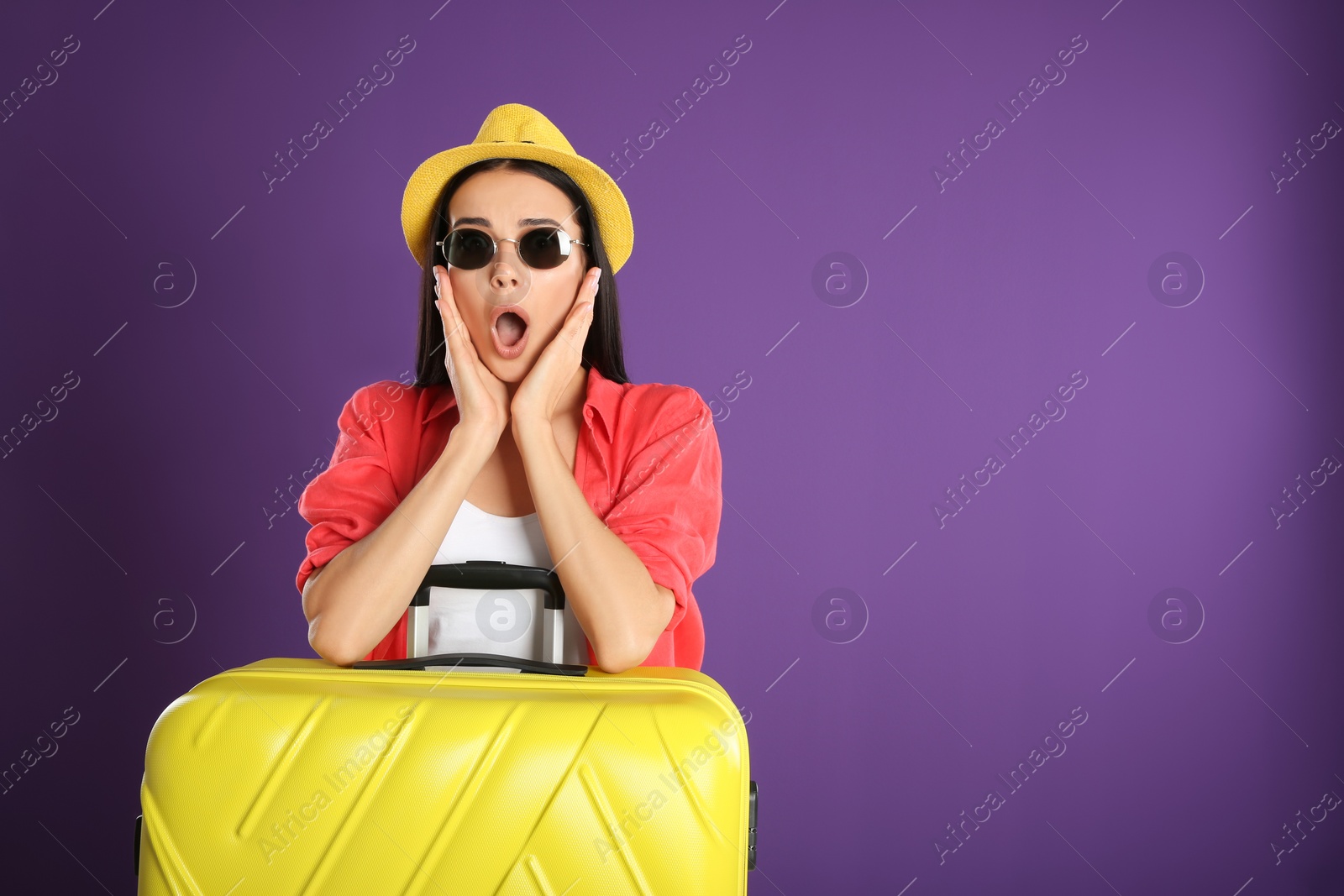 Photo of Beautiful surprised woman with suitcase for summer trip on purple background. Vacation travel