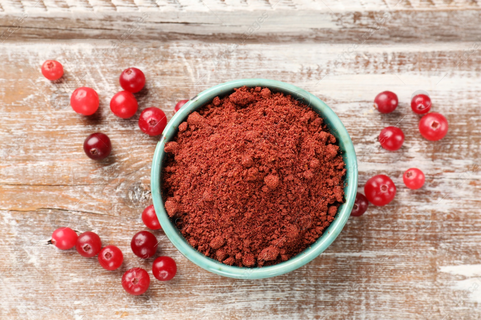 Photo of Cranberry powder in bowl and fresh berries on wooden rustic table, top view