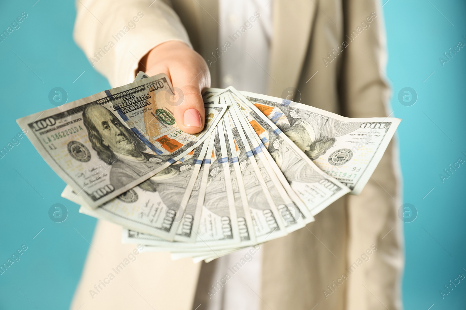 Photo of Woman holding dollar banknotes on turquoise background, closeup. Money exchange concept