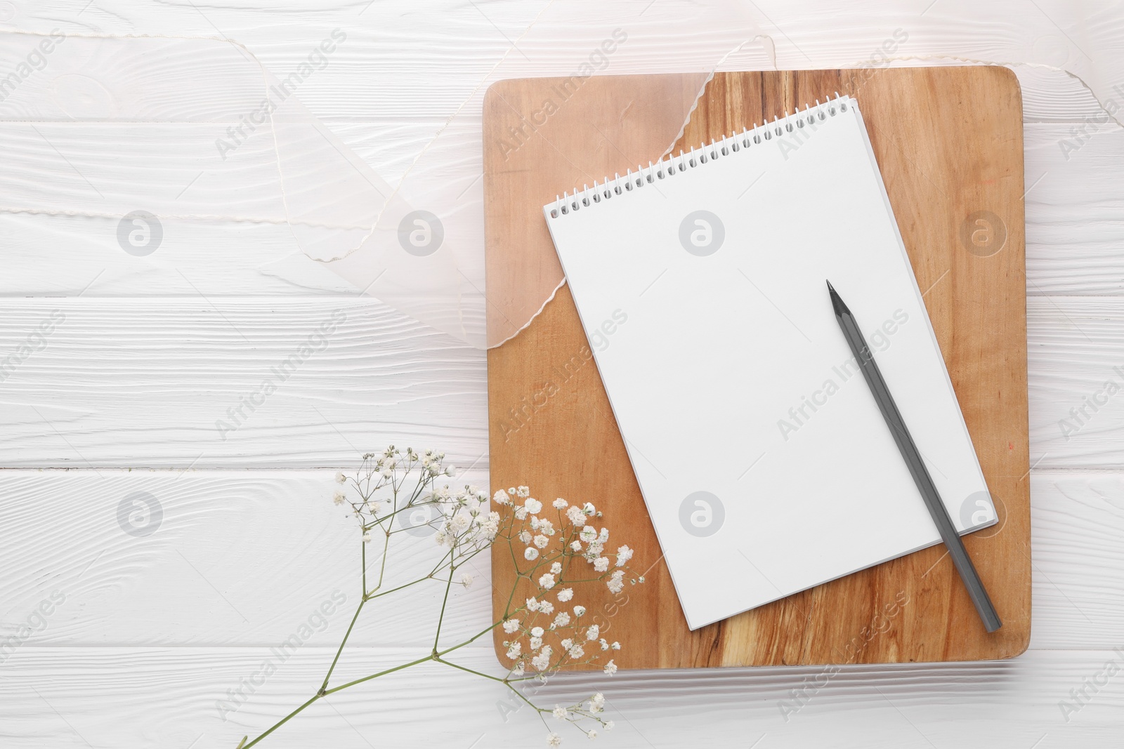 Photo of Guest list. Notebook, pencil, gypsophila and ribbon on white wooden background, flat lay. Space for text