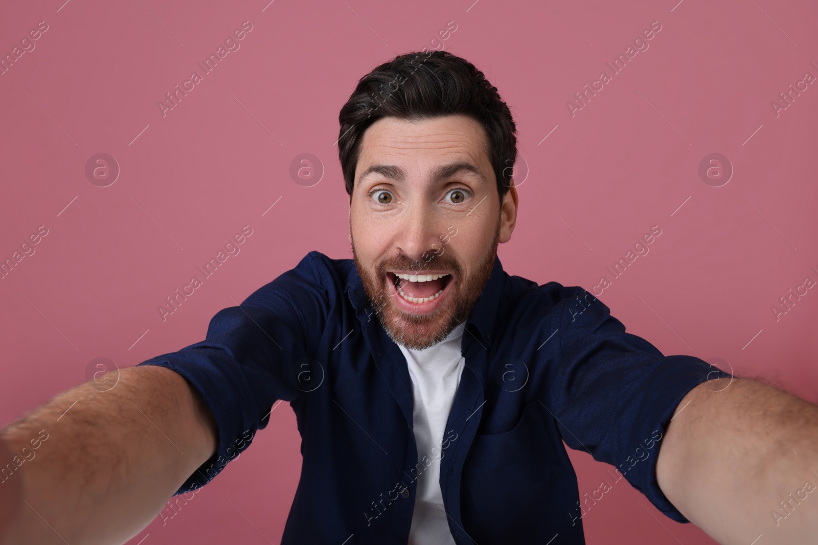 Photo of Smiling man taking selfie on pink background