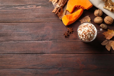 Delicious pumpkin latte on brown wooden table, flat lay. Space for text