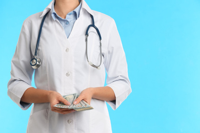 Doctor with bribe on light blue background, closeup. Corruption in medicine
