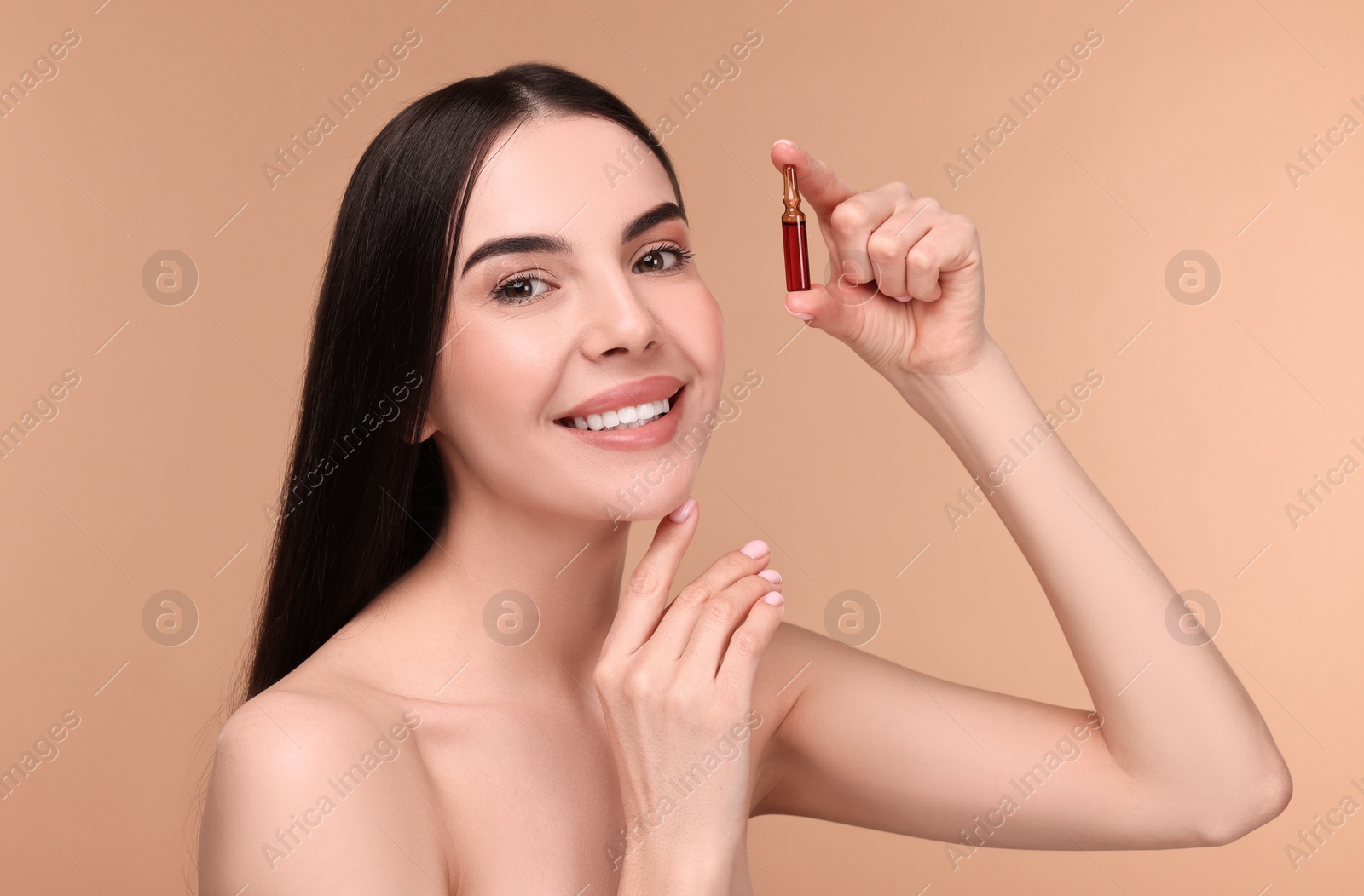 Photo of Beautiful young woman holding skincare ampoule on beige background