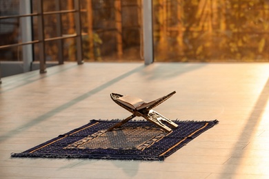 Rehal with open Quran on Muslim prayer mat indoors