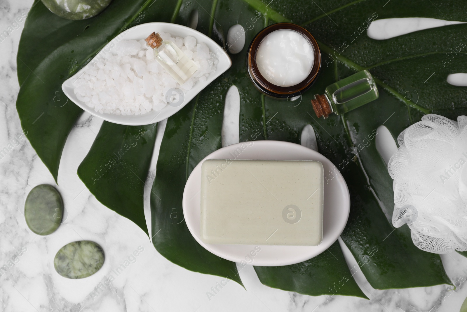 Photo of Flat lay composition with different spa products and tropical leaf on white marble table