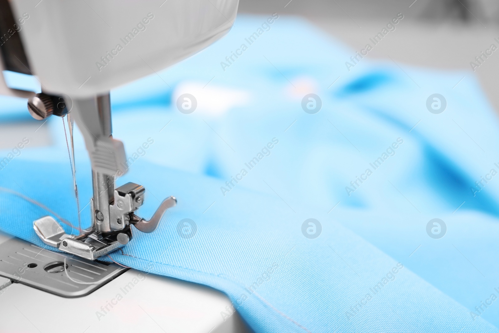 Photo of Sewing machine with fabric on table in tailor workshop, closeup