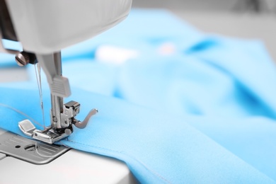 Photo of Sewing machine with fabric on table in tailor workshop, closeup