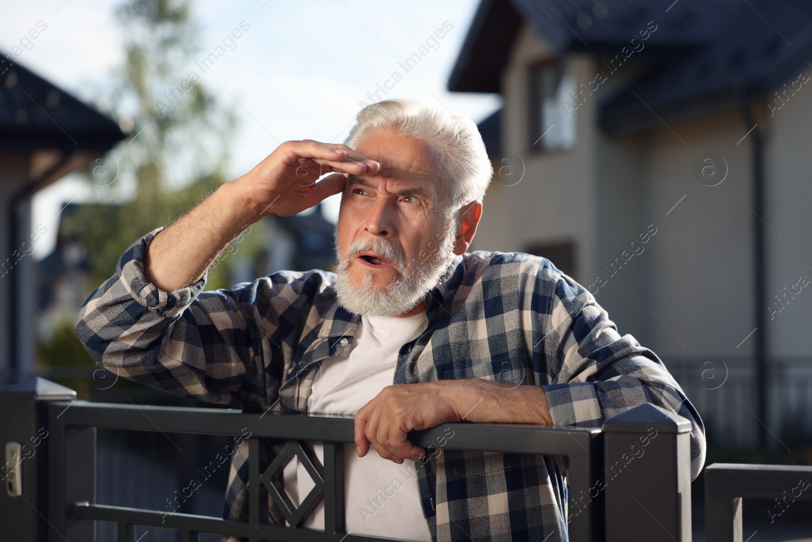 Photo of Concept of private life. Curious senior man spying on neighbours over fence outdoors