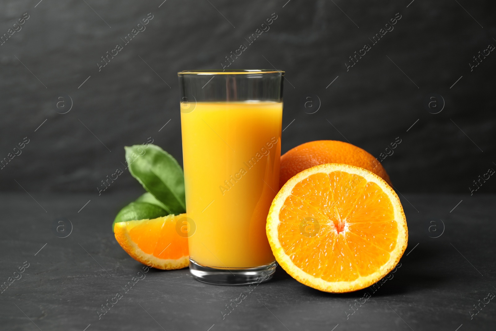 Photo of Glass of orange juice and fresh fruits on grey table