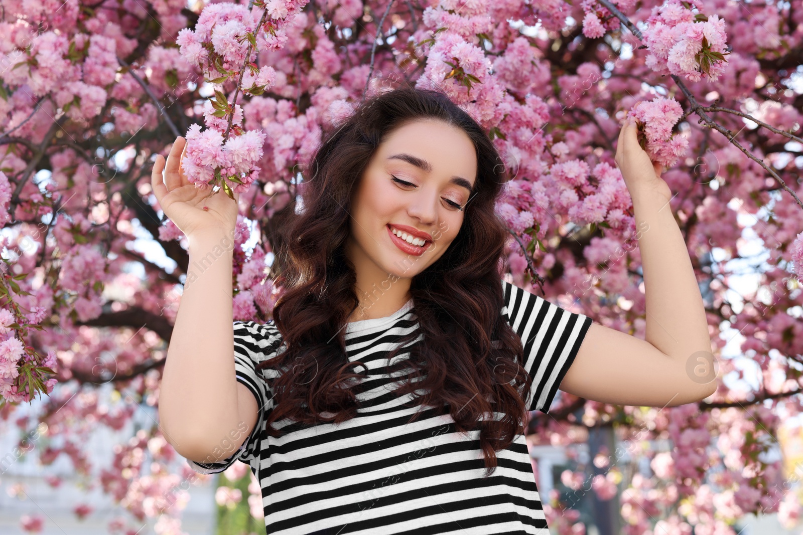 Photo of Beautiful woman near blossoming sakura tree on spring day