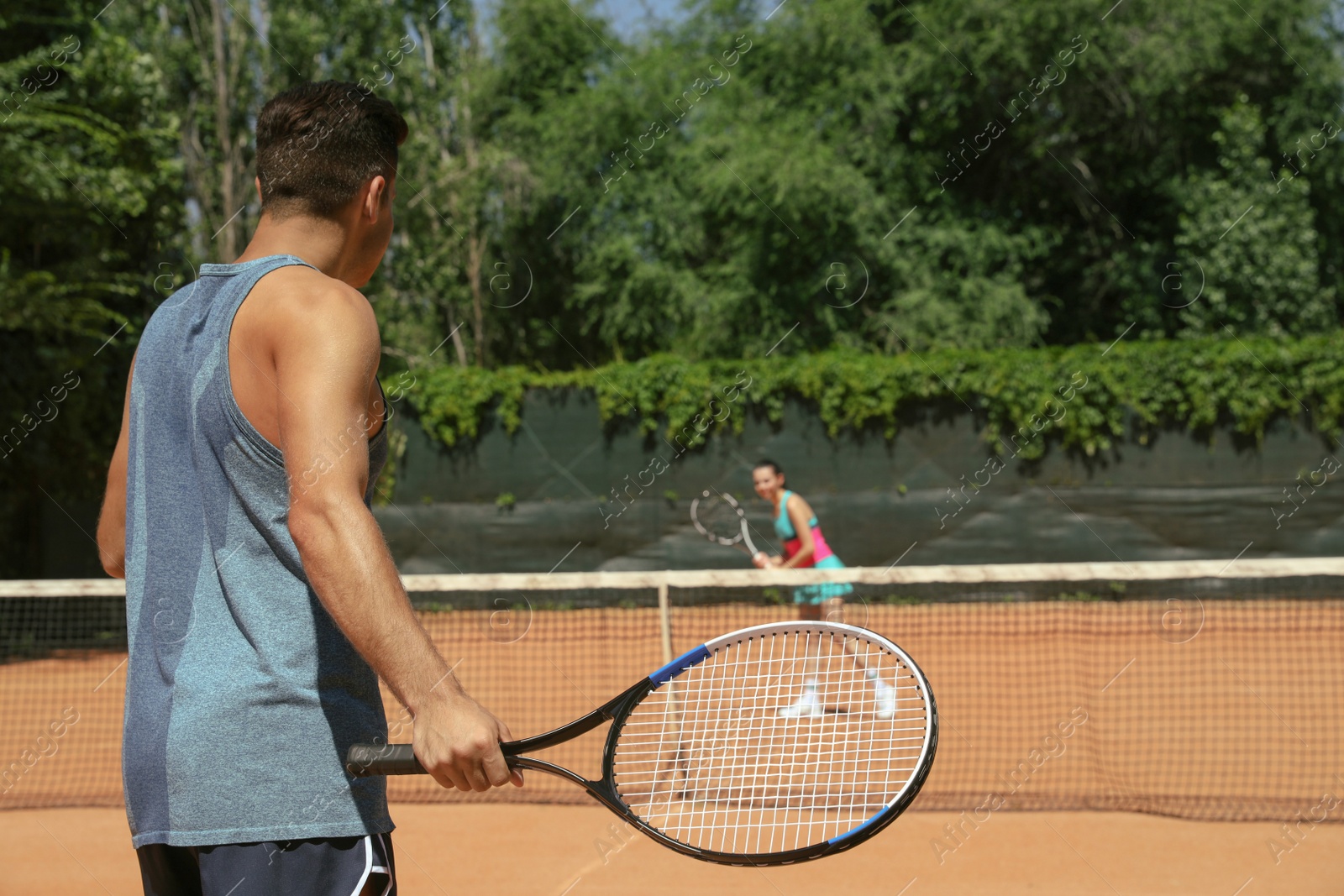 Photo of Couple playing tennis on court during sunny day