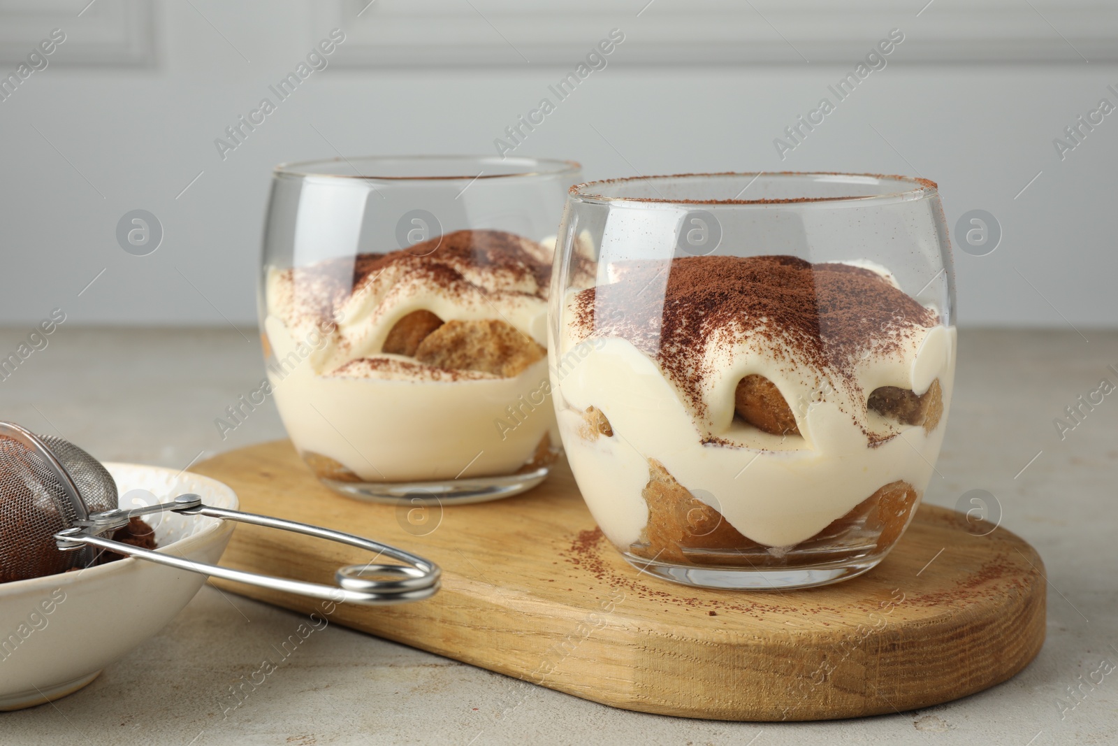 Photo of Delicious tiramisu in glasses on light table