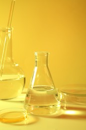 Laboratory analysis. Different glassware on table against yellow background