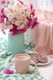 Cup of fresh coffee and beautiful bouquet on white table