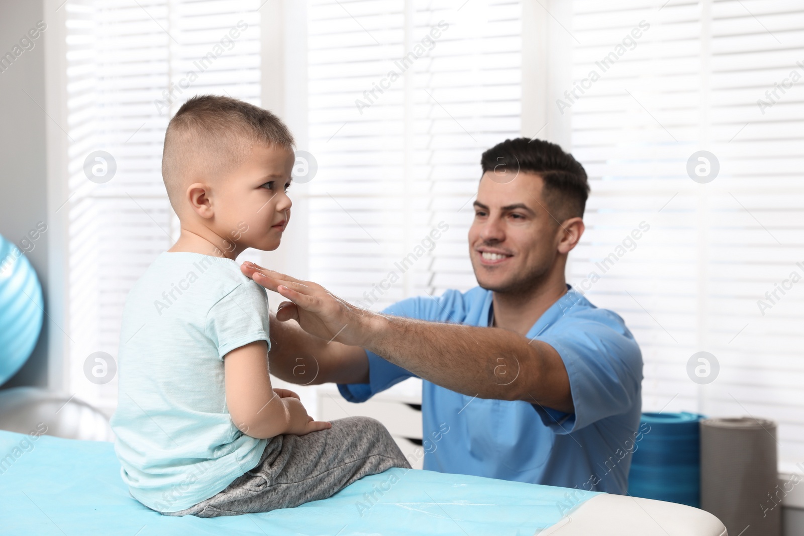 Photo of Orthopedist examining child in clinic. Scoliosis treatment