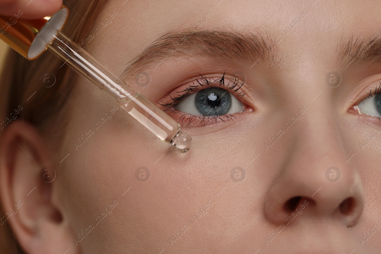 Photo of Woman applying essential oil onto face, closeup