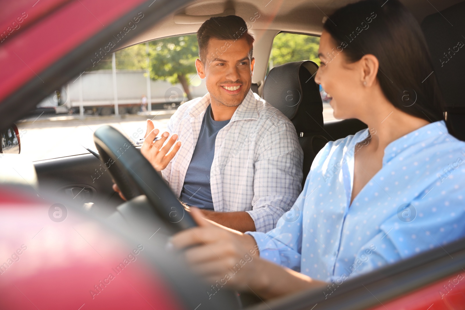 Photo of Young woman and instructor in car outdoors. Driving school