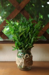Photo of Beautiful green mint in glass jar on wooden table