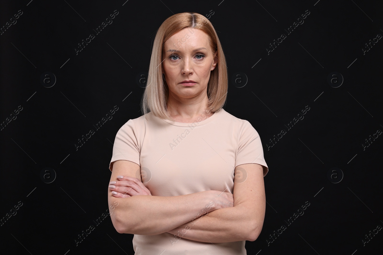 Photo of Portrait of sad woman with crossed arms on black background