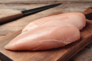 Photo of Fresh raw chicken meat on wooden cutting board