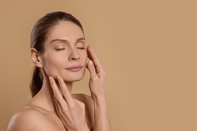 Photo of Woman massaging her face on beige background. Space for text