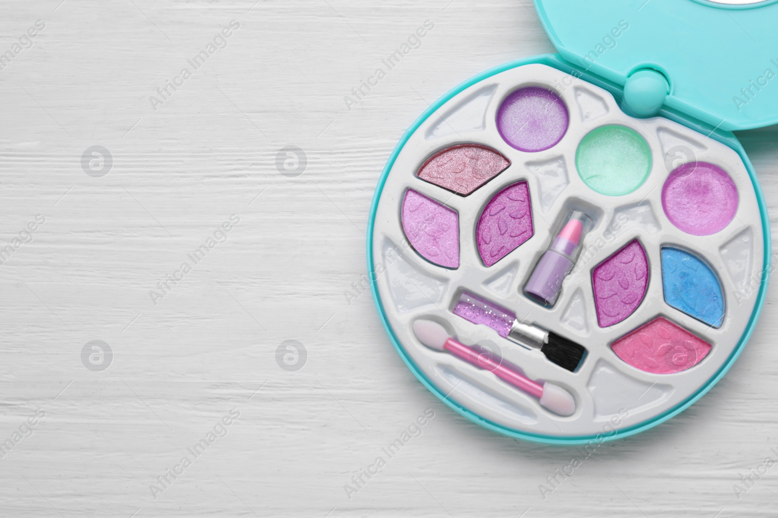 Photo of Decorative cosmetics for kids. Eye shadow palette on white wooden table, top view. Space for text