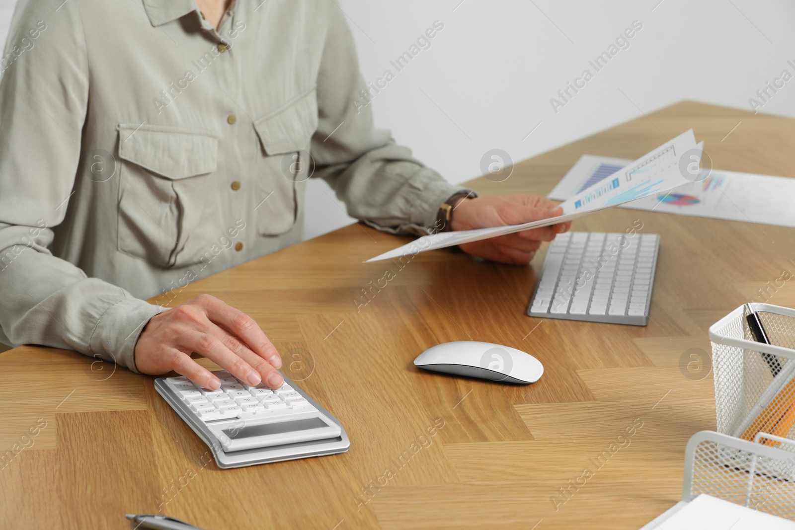 Photo of Professional accountant using calculator at wooden desk in office, closeup