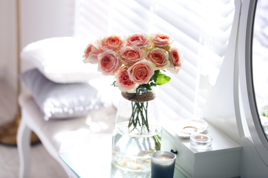 Photo of Glass vase with beautiful flowers on dressing table in modern room interior