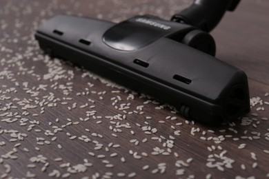 Vacuuming scattered rice from wooden floor, closeup