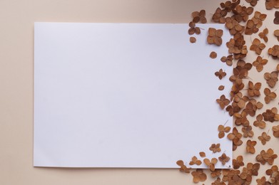 Dried hortensia flowers and sheet of paper on beige background, flat lay