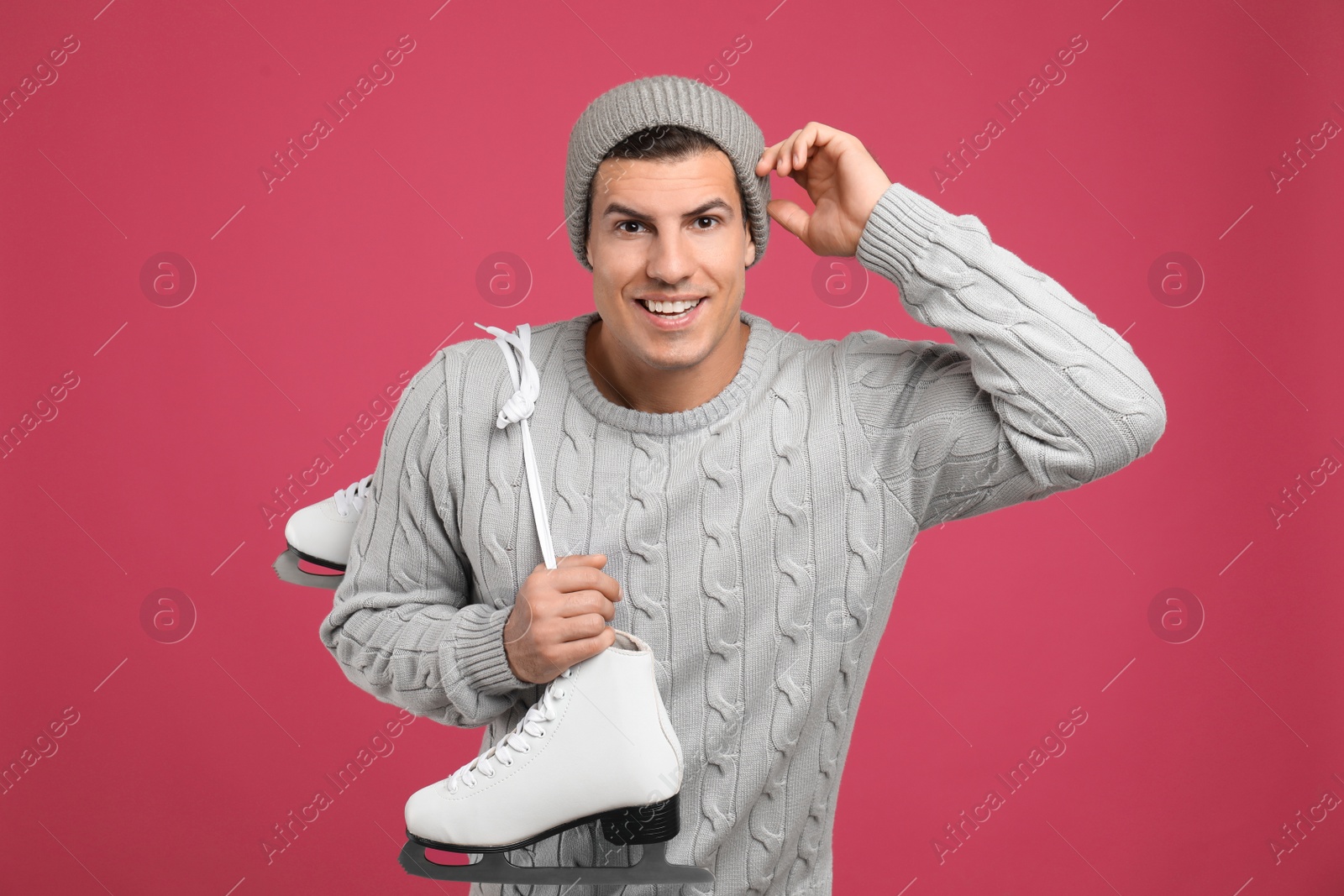 Photo of Happy man with ice skates on pink background